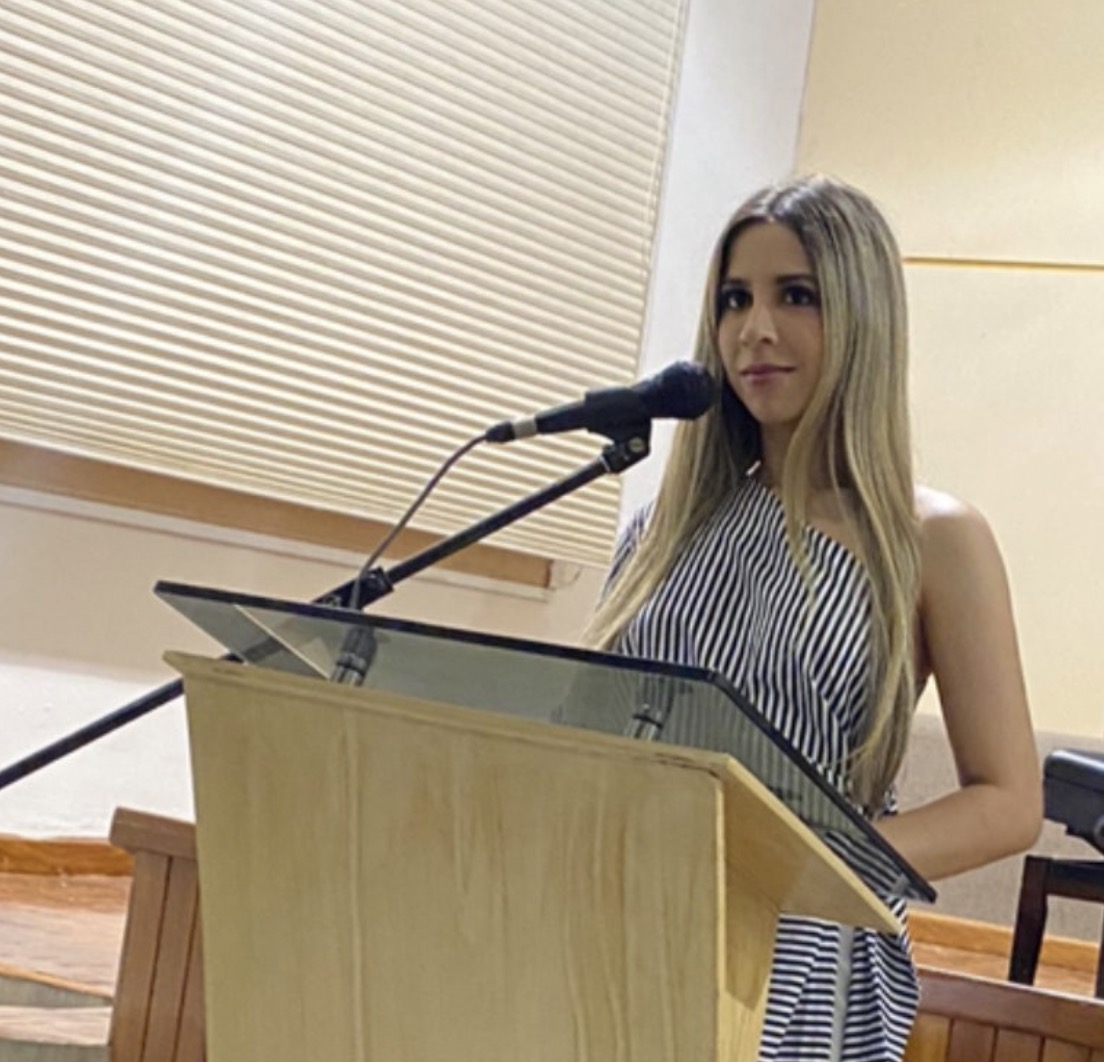 Valeria Rocha frente al micrófono en un atril durante un evento