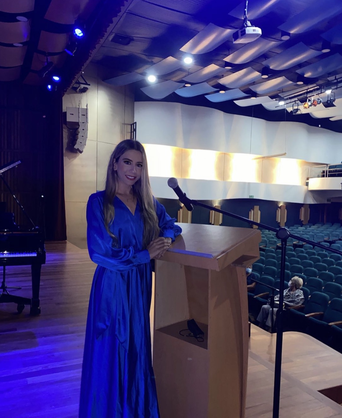 Valeria con micrófono y público en un auditorio